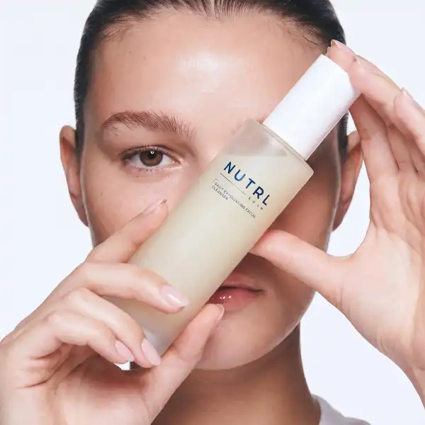 Woman holding a NUTRL bottle up to her face